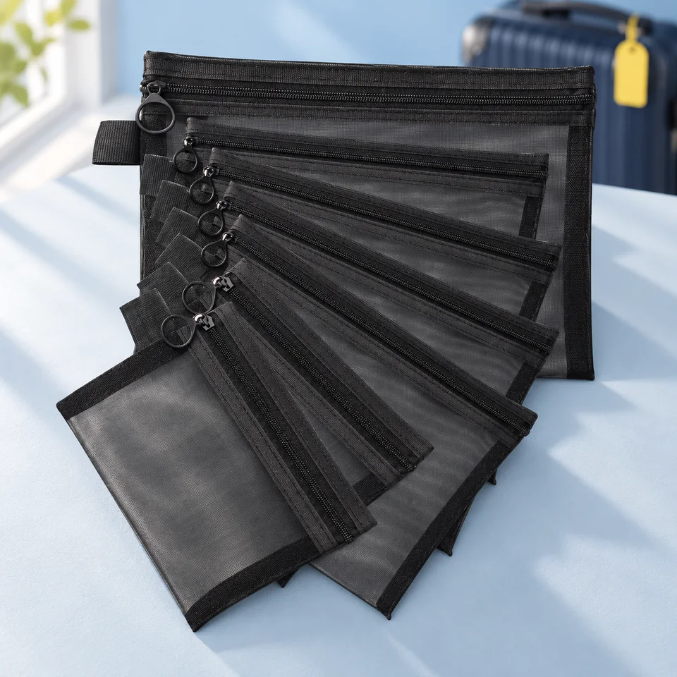NVGVUP — sept petites trousses en maille noire de NVGVUP, mise en situation dans un univers de voyage bleu-gris