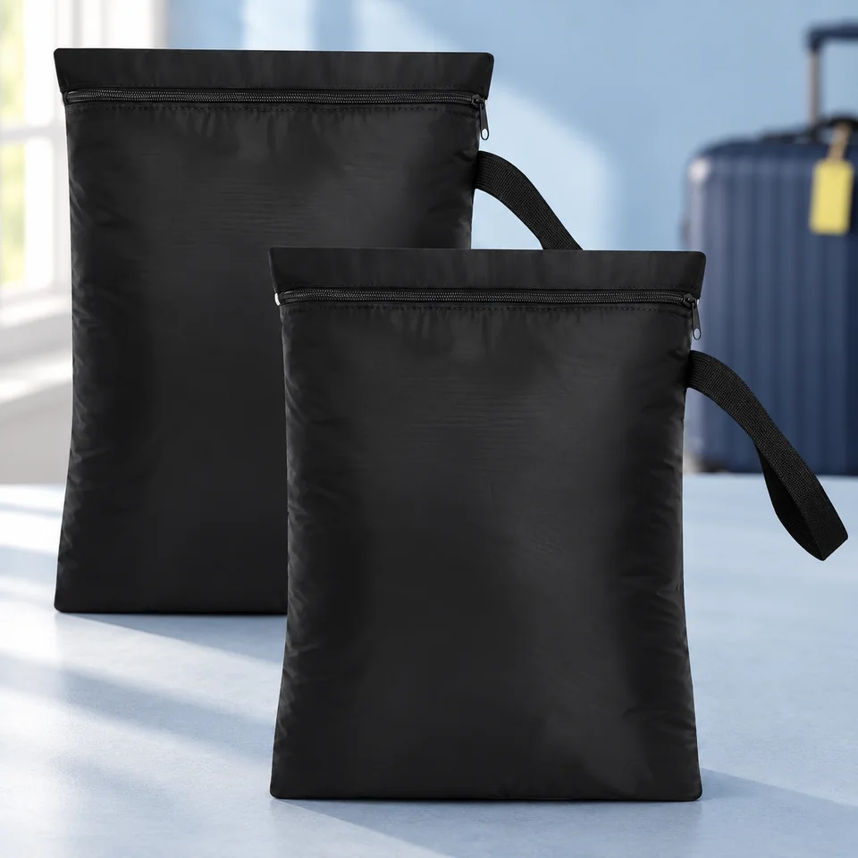 OTraki — deux sacs à linge noirs de 30 × 40 cm de OTraki, mise en situation dans un univers de voyage bleu-gris